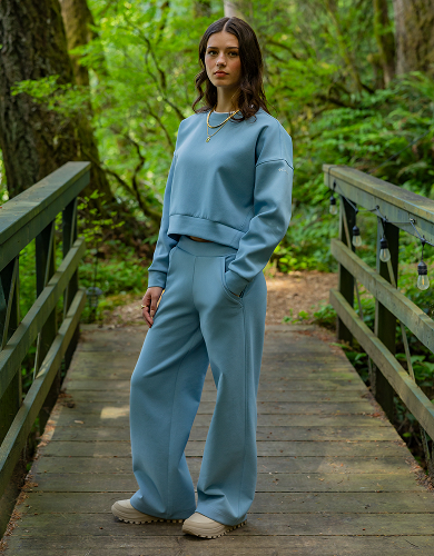 A woman wearing a blue sweat set in a forest.
