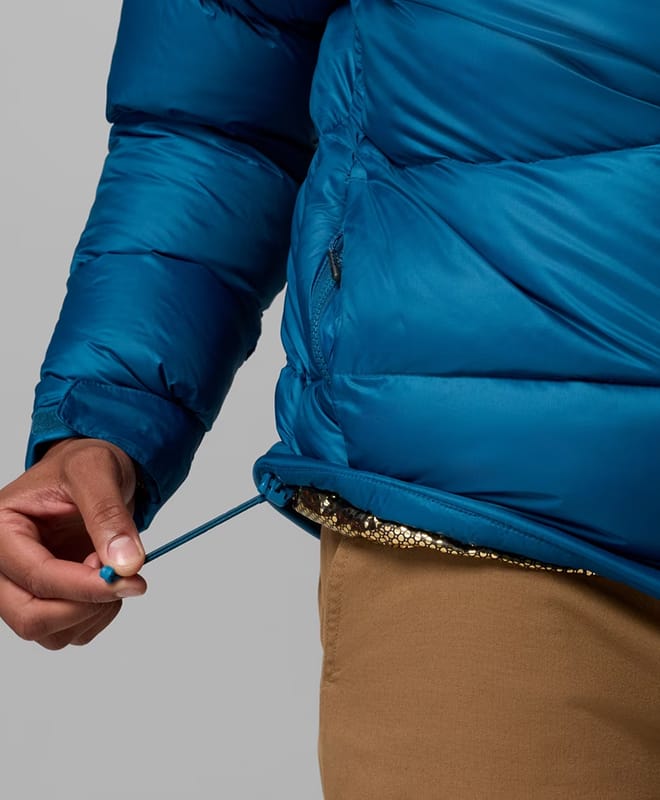 Close-up of a man pulling at the drawstring cord of his blue puffer.