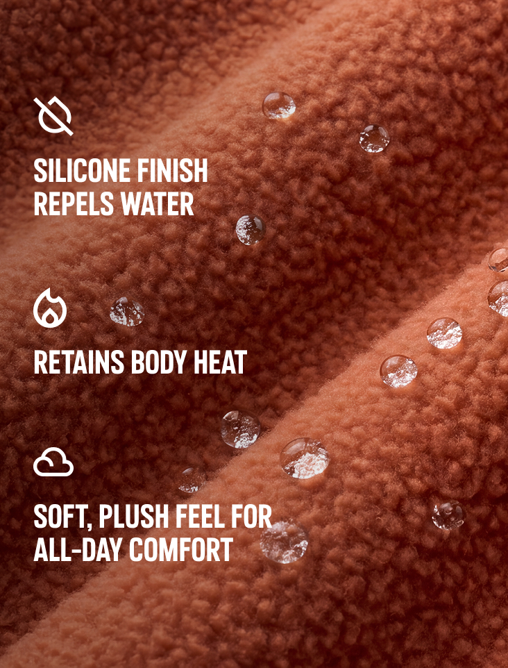 Close-up of orange fleece texture with text: SILICONE FINISH REPELS WATER, RETAINS BODY HEAT, SOFT PLUSH FEEL FOR ALL-DAY COMFORT