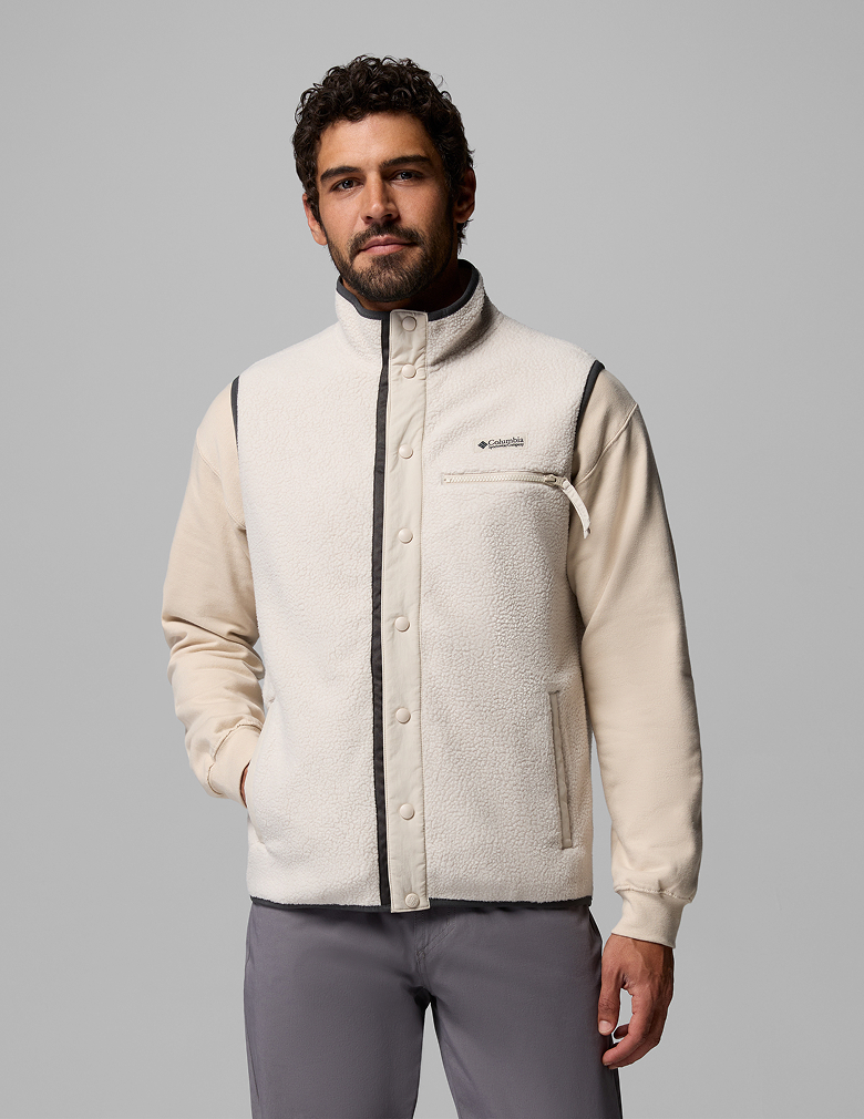 A man wearing a white long sleeve shirt and fleece vest.