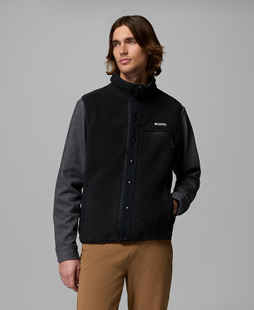 A man wearing a gray long sleeve shirt and black fleece vest.