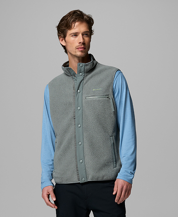A man wearing a blue long sleeve shirt and green fleece vest.