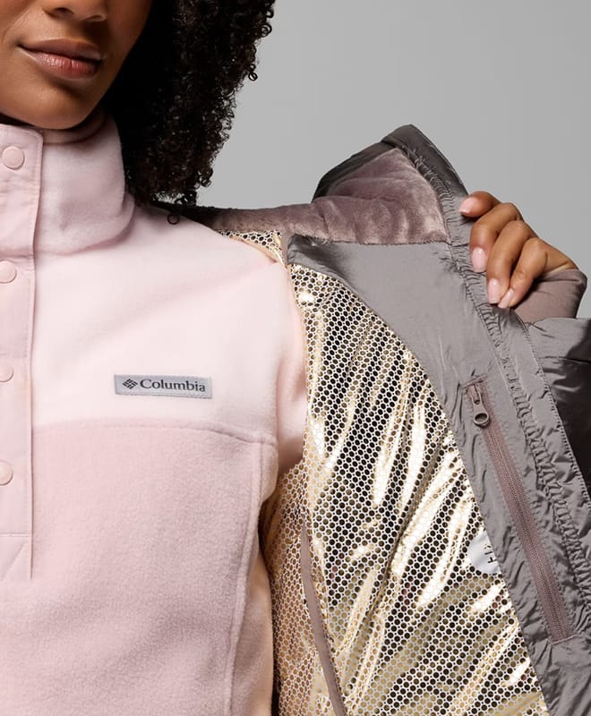A woman opening her gray jacket to reveal the gold interior.