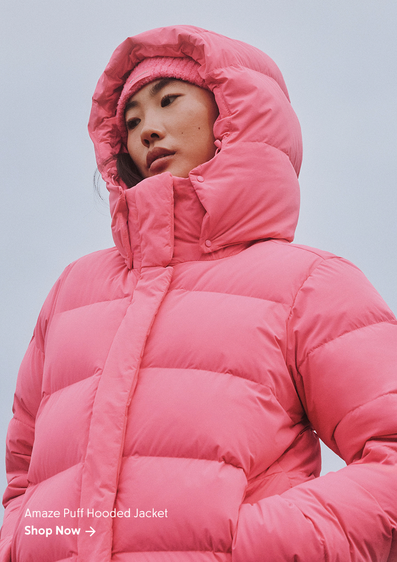 A woman wearing a pink puffer jacket against a cloudy sky with text: Amaze Puff Hooded Jacket Shop Now