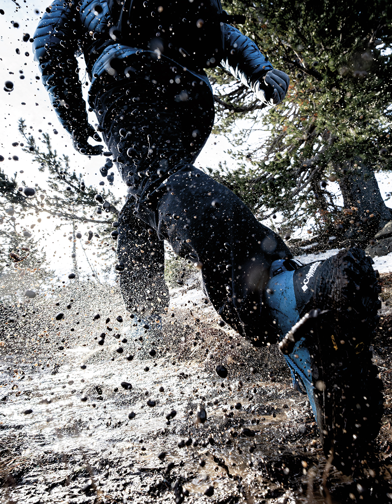 Close up shot of hiker talking through muddy puddles in Peakfreak with mud splashing up everywhere. 