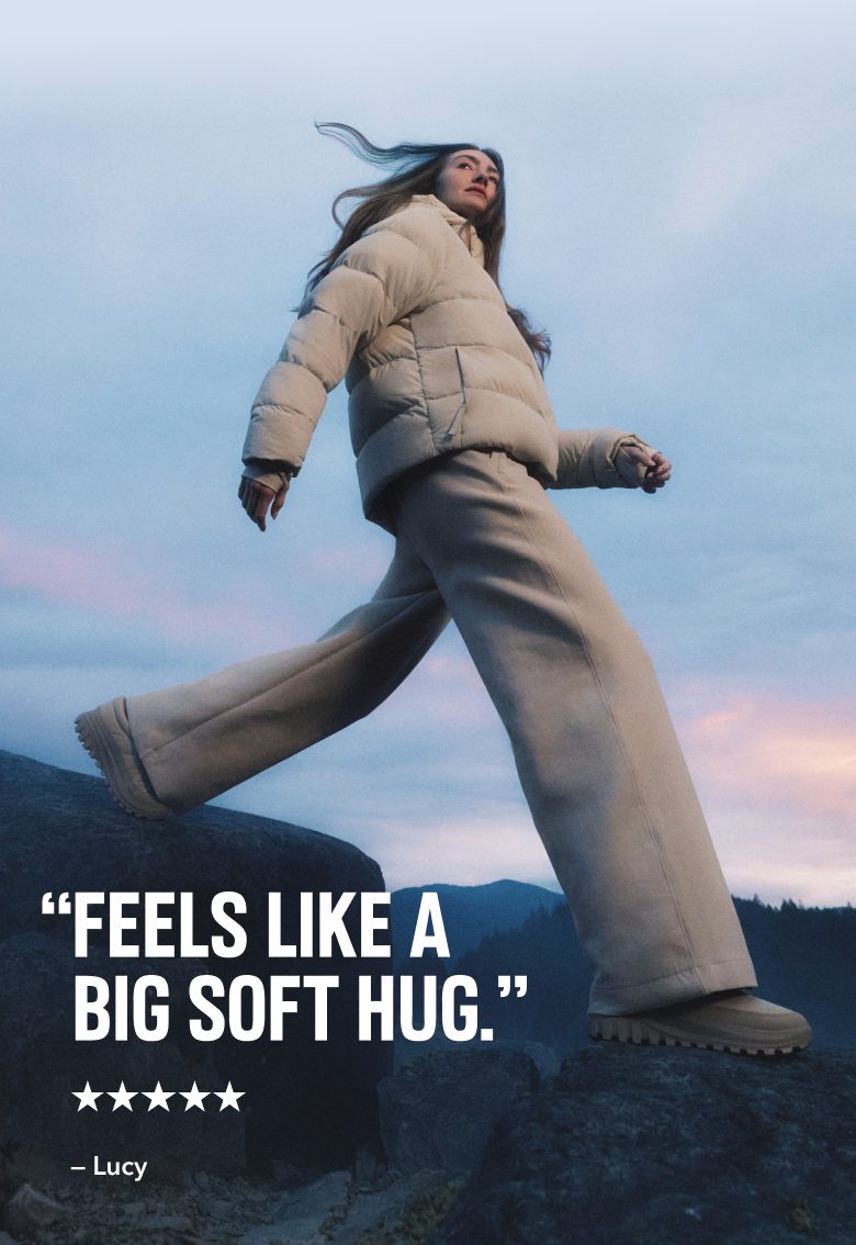 A woman in a white puffer jacket, walking against a twilight sky with text: 