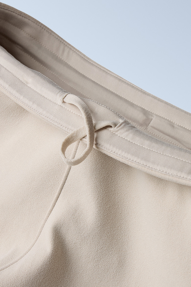 Flatlay of white sweat pants against a grey background.