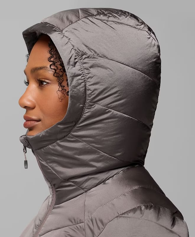 A woman wearing a gray puffer with the hood up.