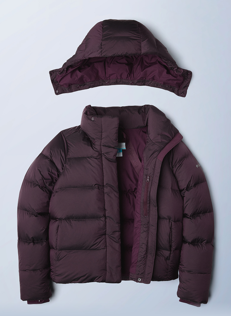 Flatlay of a purple puffer jacket against a blue background.